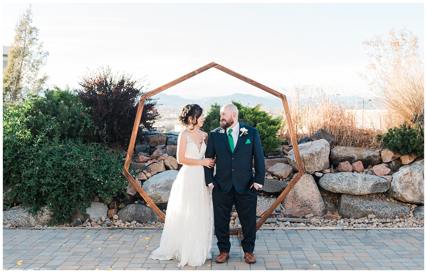 Bride and groom stand side by side turning their heads toward one another in front of a hexagonal arch at their alter spot during the best month to get married in Colorado