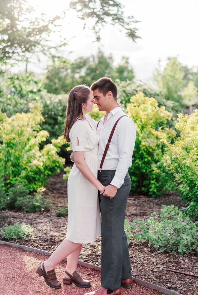 Two young people kiss near a glowy bush for Denver photographer