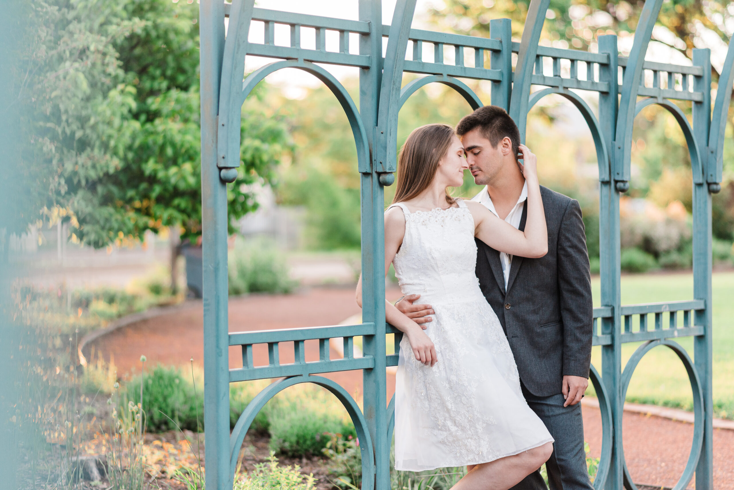 Denver photographer captures a young couple in a garden leaning against a green bridge Colorado Wedding Photographer