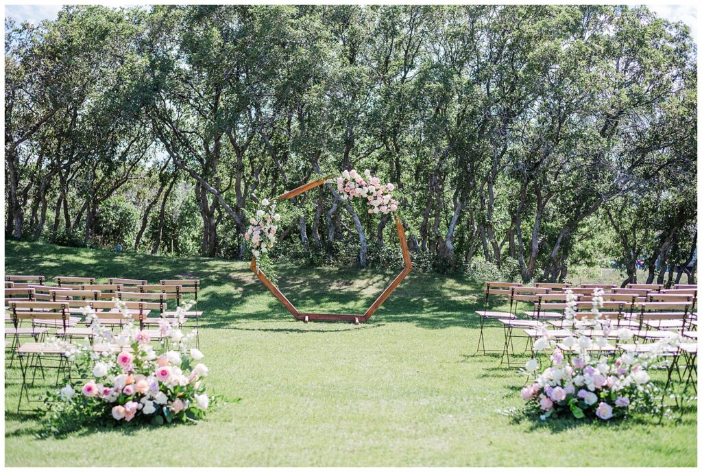 Outside ceremony set up with an octagonal arch covered in pink and green florals at The Oaks