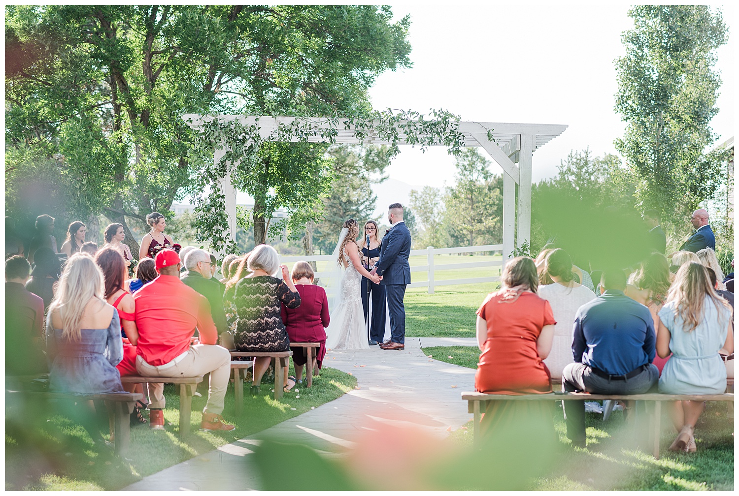 Couple exchange vows outside under an arch outside surrounded by friends and family after planning a wedding for a full year.